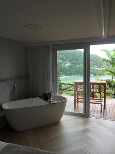 a large bath tub in a room with a balcony at Mar de Bougainville in Governador Celso Ramos