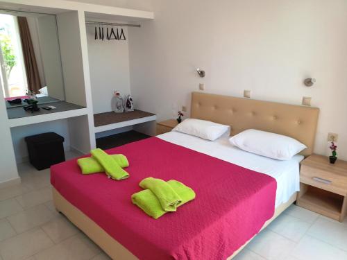 a bedroom with a bed with two lime green towels on it at Villa Maroula in Afantou