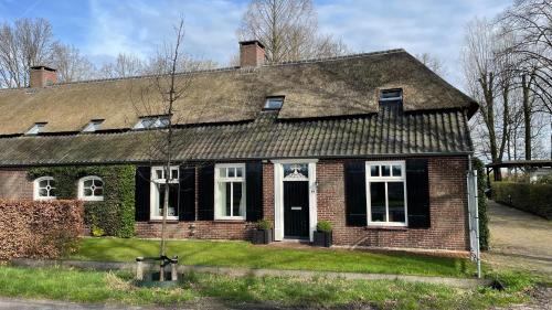 an old brick house with a shingled roof at Hoeve bij Vosselen in Asten