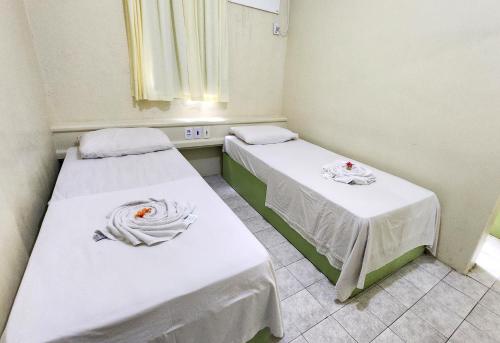 two beds in a hospital room with white sheets at Guarany Hotel Express in João Pessoa