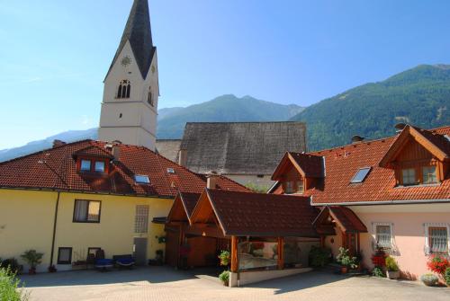 a building with a church with a clock tower at Frühstückspension Kirchenwirt in Obervellach