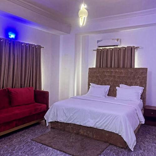 ein Schlafzimmer mit einem Bett und einem roten Sofa in der Unterkunft Dew Shortlet Apartment in Port Harcourt