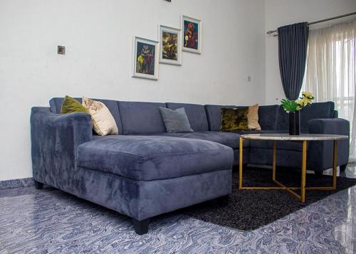 ein blaues Sofa im Wohnzimmer mit einem Tisch in der Unterkunft Dew Shortlet Apartment in Port Harcourt