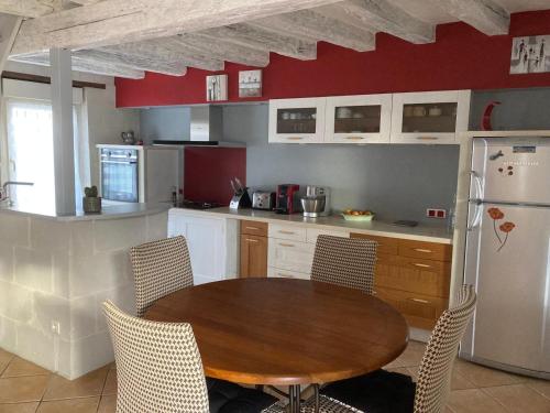 une cuisine avec une table en bois et un réfrigérateur dans l'établissement Maison les palmiers, à La Bohalle