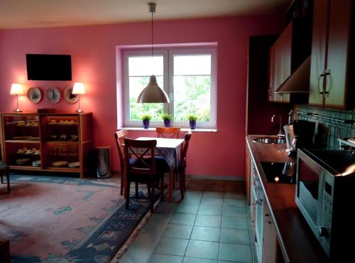 een rode keuken met een tafel en een raam bij Ferienwohnung in der Kaschubei, in ruhiger Lage am Waldrand, in der Nähe von Danzig und Sopot in Sulmin