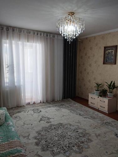 een woonkamer met een kroonluchter en een groot tapijt bij Muras in Naryn