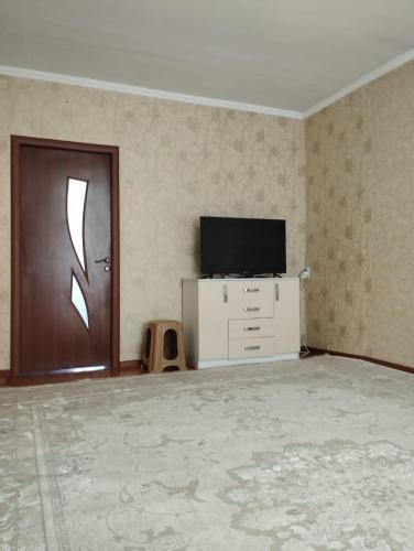 een lege kamer met een deur, een tv en een kast bij Muras in Naryn