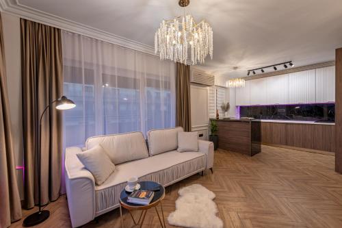 a living room with a white couch and a chandelier at The Episode - Jacuzzi Penthouses in Cluj-Napoca