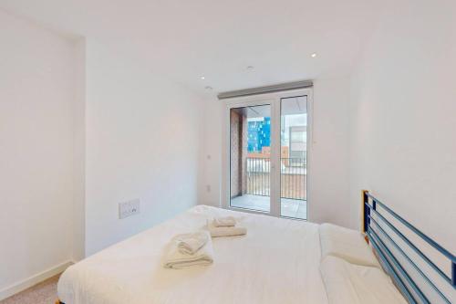 a white bedroom with a bed and a window at 1Bed apt in Whitechapel with a balcony & near tube in London