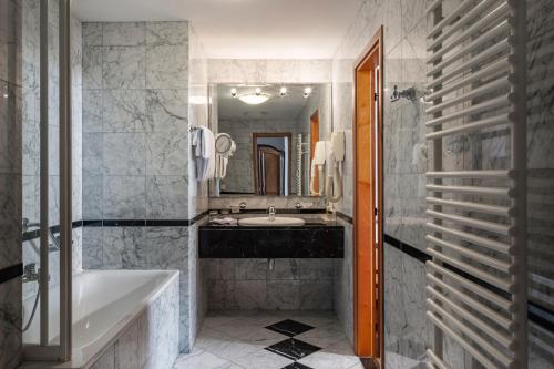 a bathroom with a tub and a sink and a mirror at Grand Hotel Bonavia in Rijeka