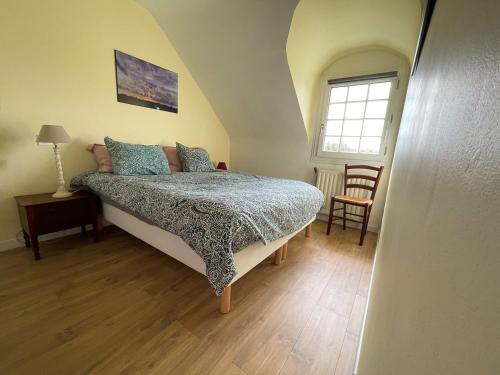 Un dormitorio con una cama y una ventana y una silla. en Maison vue sur les alignements de Carnac - Les Glycines, en Carnac