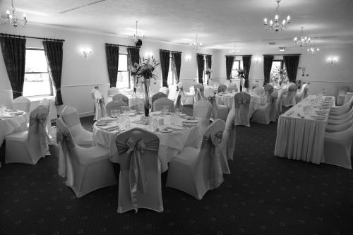 a room filled with tables and chairs with white linens at Marsh Farm Hotel in Royal Wootton Bassett