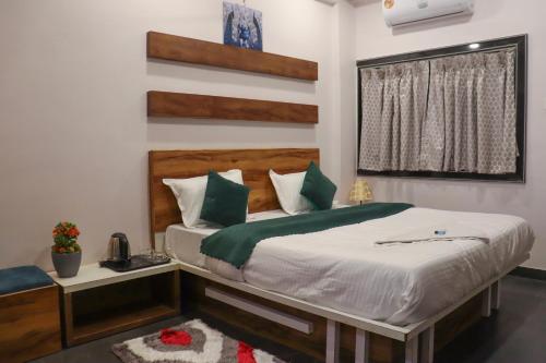 um quarto com uma cama com almofadas verdes e brancas em Hotel Garuda Executive Latur em Lātūr