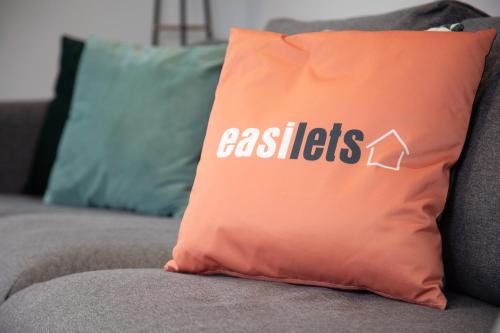 an orange pillow on a couch with the words assists at 3 Bedroom lodge with hot tub in York