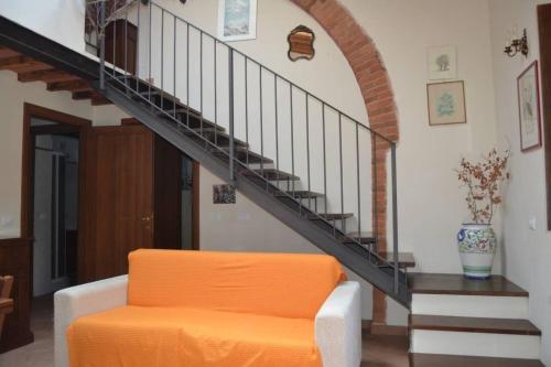 una sedia arancione in un soggiorno con scala di Wohnung auf der ersten Etage a Campiglia Marittima