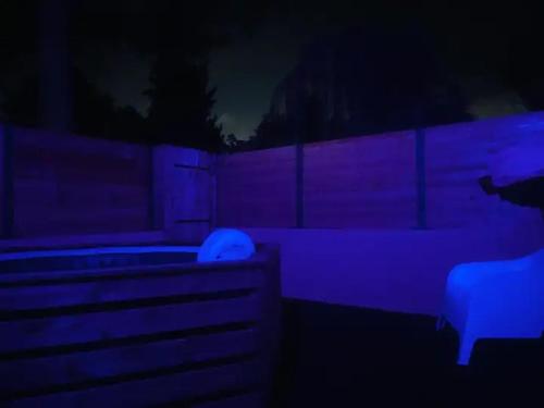 une chambre sombre avec des lumières violettes et un banc dans l'établissement JACUZZI Aixclusive, au Tholonet