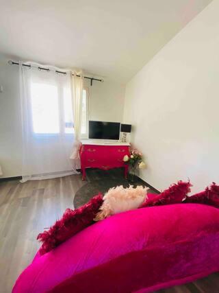 Cette chambre comprend un grand lit rose et un bureau. dans l'établissement JACUZZI Aixclusive, au Tholonet
