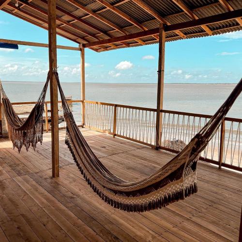 a hammock on a deck with a view of the ocean at Hostel Capitão da Ilha in Maracanã