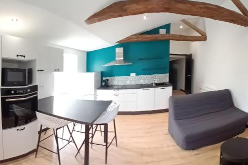 a kitchen with a table and chairs and a blue wall at Charmant logement atypique et calme in Mouchamps