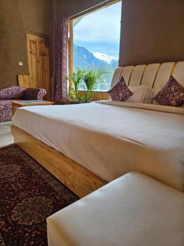 a bedroom with a large bed with a large window at Hotel Old Manali with Balcony and Mountain Views, Near Manali Mall Road in Manāli
