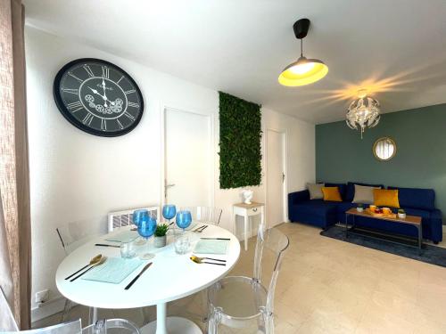ein Wohnzimmer mit einem Tisch und einer Uhr an der Wand in der Unterkunft Les Entrepreneurs - Appartements neufs et spacieux, proche RER C et Aéroport Orly in Morangis