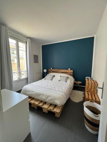 - une chambre avec un lit et un mur bleu dans l'établissement Moma home, à Poissy