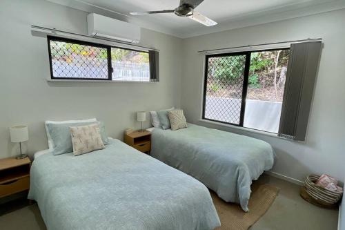 two beds in a room with two windows at New Pool Now Open! - Trinity Beach Haven - Luxury 4 bedroom home, Steps to the Beach, Surrounded by Mountains in Trinity Beach