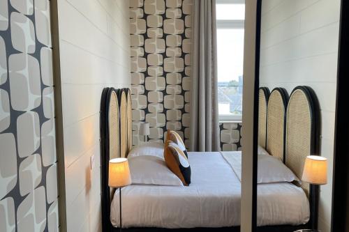 a room with a bed with a mirror and a window at Hôtel Les Costans, The Originals Relais in Perros-Guirec