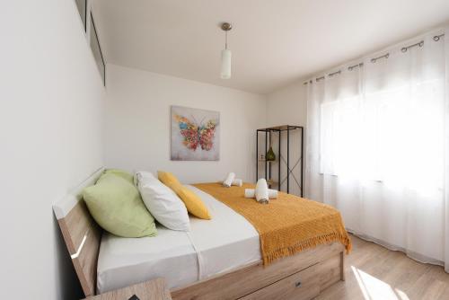 a bedroom with a bed with yellow and green pillows at Sunset Beach Suites in Kožino