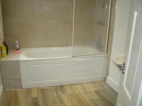 La salle de bains est pourvue d'une douche et d'une baignoire blanche. dans l'établissement Contractors House Edgbaston, à Birmingham