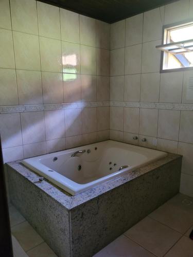 a large bath tub in a bathroom with a window at Pousada Mirante Santo Antônio in São José do Rio Preto