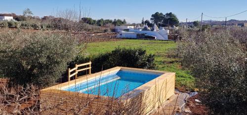 a swimming pool in the middle of a field at Trulli Beauty LAMIA in Martina Franca