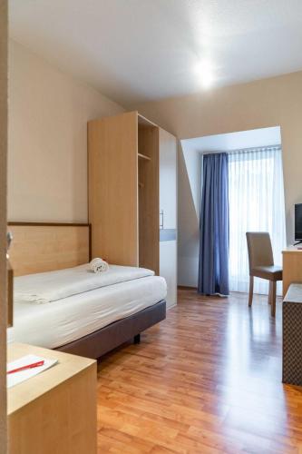 a hotel room with a bed and a desk at Astoria City Resort in Essen