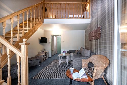 a living room with a staircase and a couch at Nykščio Namai & SPA in Anykščiai
