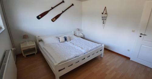 1 dormitorio con 1 cama blanca y 2 instrumentos en la pared en Haus Hygge - Ferienwohnung Anker en Boren