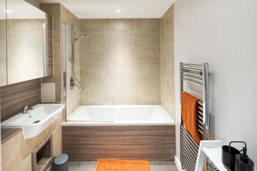 a bathroom with a tub and a sink at Canning town -2 bed Luxury Apartment in London
