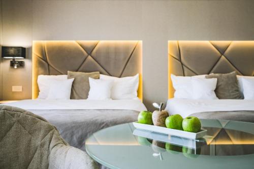 a hotel room with two beds and a glass table at Hotel Eden Garden Spa in Câmpulung Moldovenesc