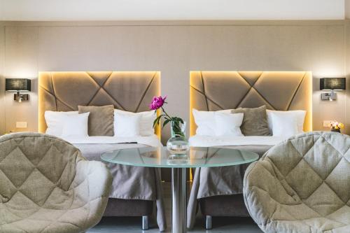 a hotel room with two beds and a table and two chairs at Hotel Eden Garden Spa in Câmpulung Moldovenesc