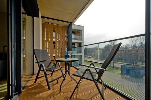 a balcony with a table and chairs and a large window at Apartamenty Wydma & Las BlueApart in Jastarnia