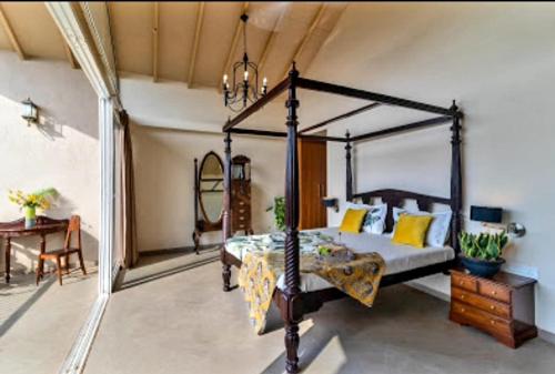 um quarto com uma cama de dossel e uma mesa em The Woods Worth Villa em Vani