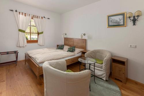 a bedroom with a bed and two chairs and a table at Hiša Ojstrica in Solčava