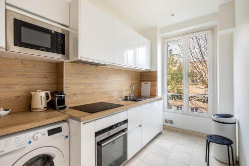 une cuisine avec un évier et un lave-vaisselle dans l'établissement GuestReady -Apt familial en bordure de la Capitale, à Levallois-Perret