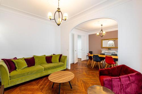 een woonkamer met een groene bank en een tafel bij GuestReady -Apt familial en bordure de la Capitale in Levallois-Perret