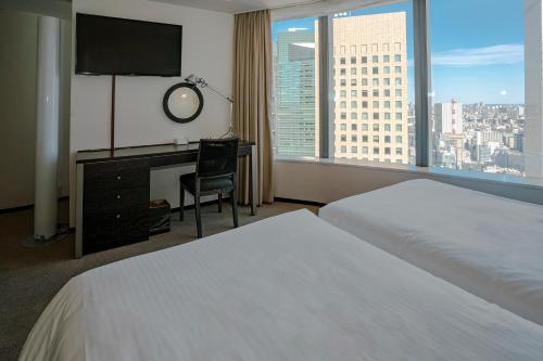 a hotel room with a bed and a desk with a television at Park Hotel Tokyo in Tokyo