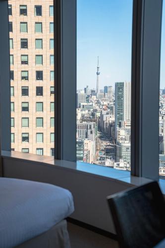a bedroom with a view of a city from a window at Park Hotel Tokyo in Tokyo