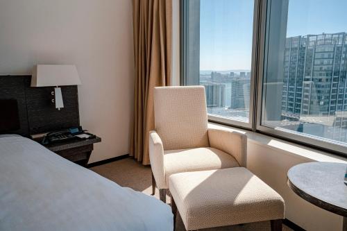 a hotel room with a bed and a chair and a window at Park Hotel Tokyo in Tokyo