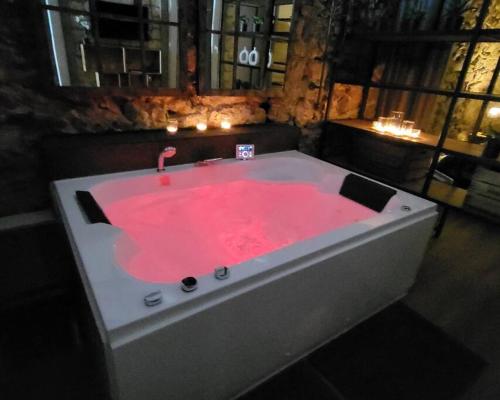 eine pinkfarbene Badewanne mit Kerzen in einem Zimmer in der Unterkunft Le 79 Balnéo Loft Déco Authentique Centre climatisation in Sète