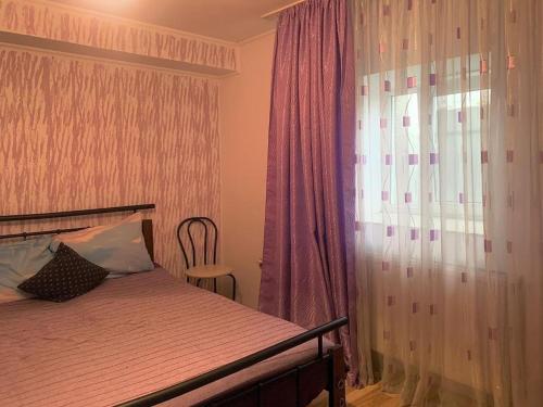 マンガリアにあるMary Holiday Houseのベッドルーム1室(紫色のカーテンと窓付きのベッド1台付)