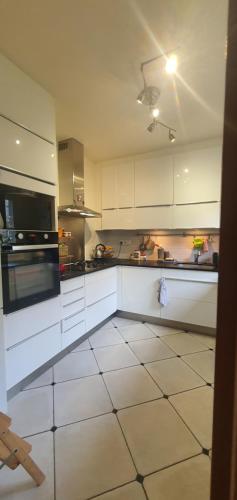 Il comprend une cuisine avec des placards blancs et du carrelage blanc. dans l'établissement Beaux Rêves à Saint-Michel, à Saint-Brieuc