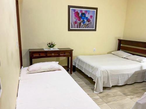 a room with two beds and a table and a picture at Paraíso Panorâmico Beira do Lago in Caldas Novas
